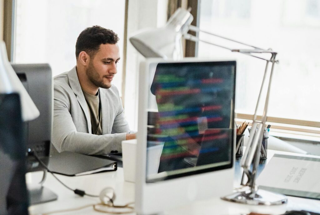 Man wearing a blazer using a hot desk in an office