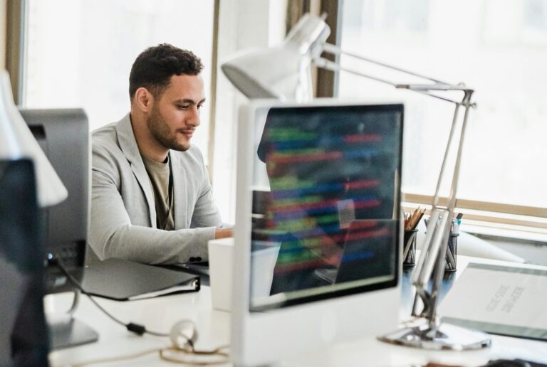 Man wearing a blazer using a hot desk in an office