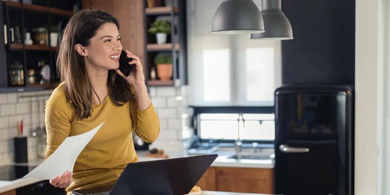 Woman talking on the phone at a desk in front of her laptop